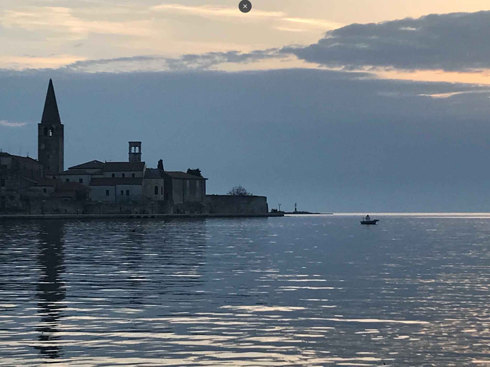 A coastal town with historic buildings, a prominent tower, and calm waters.