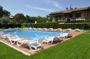 A swimming pool with lounge chairs and a house in the background.
