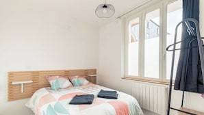 A bedroom with a bed, a radiator, a window, and a hanging rack. - Cosy, modern air-conditioned T2 (Villeurbanne)