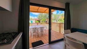 Une pièce dotée d’une porte-fenêtre coulissante donnant sur une terrasse extérieure avec une table et des chaises.