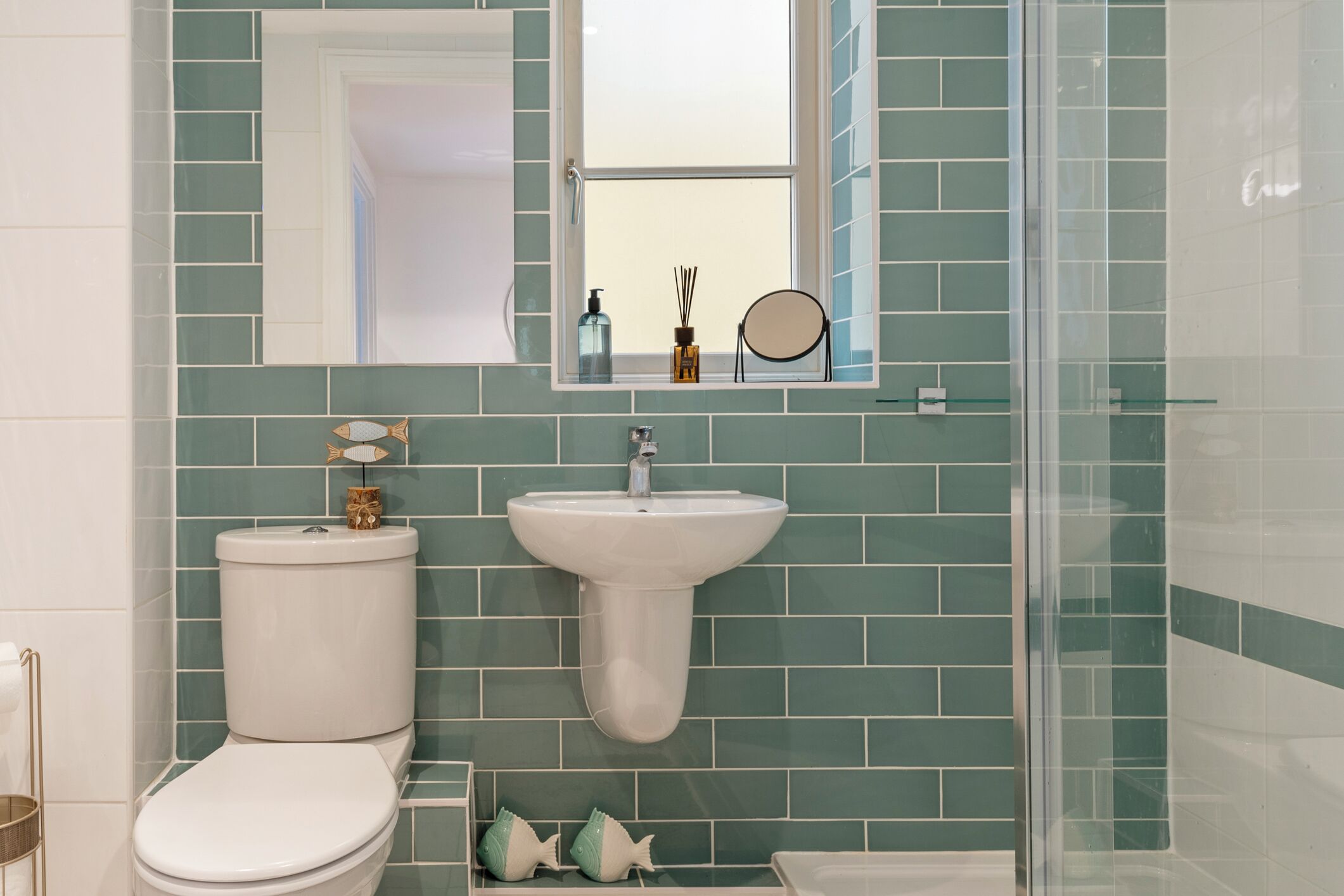 A bathroom with a toilet, sink, and glass shower enclosure.