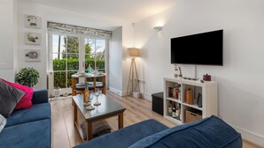 Una sala de estar con un sofá, una mesa de centro, un televisor y una estantería.