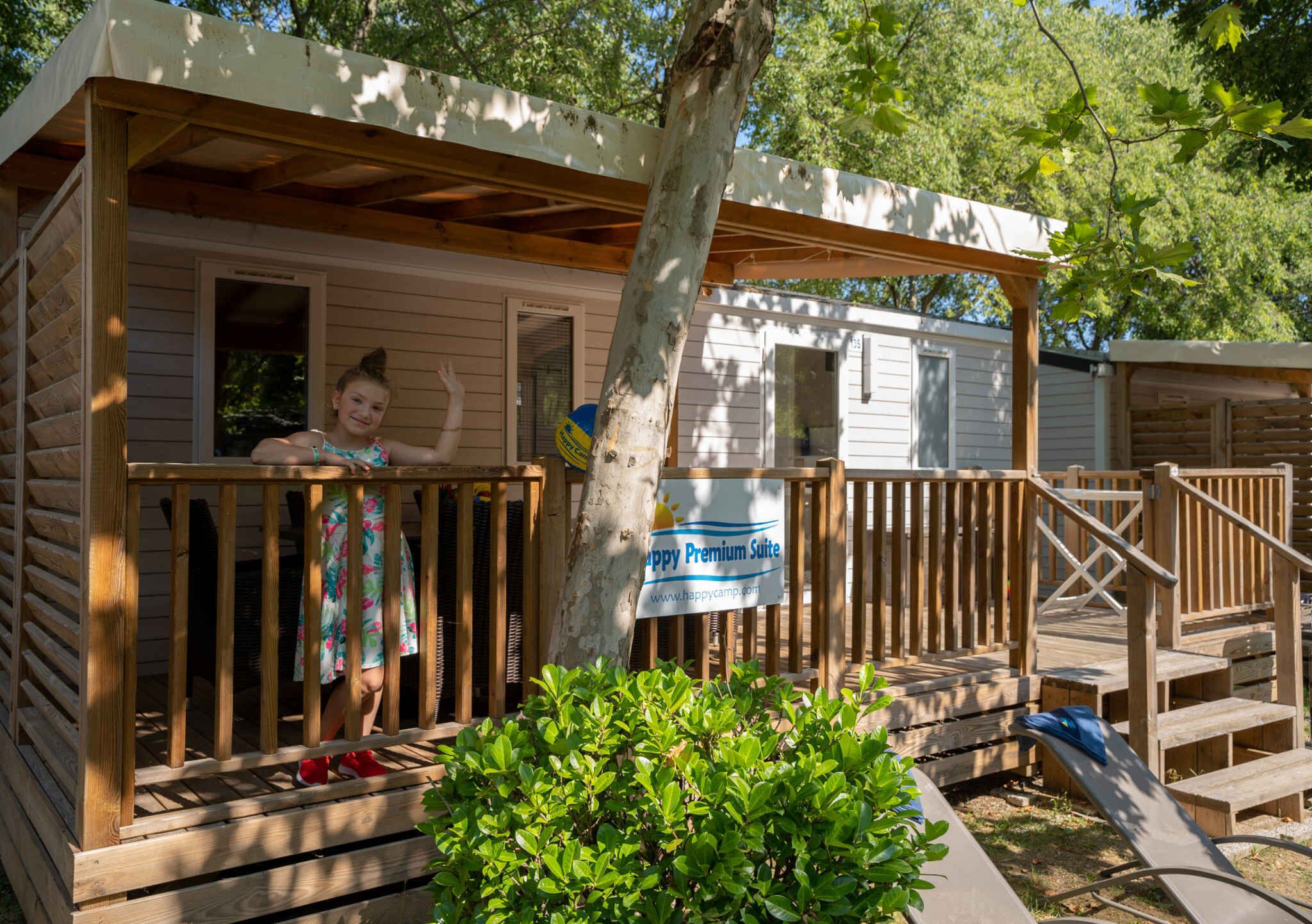 Une cabane en bois avec un porche, une enseigne indiquant une suite de luxe, et une petite terrasse.