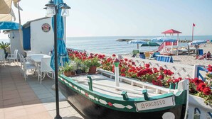 A boat named "Ragossso" docked at a beachside café with outdoor seating and a view of the sea. - Mobilehome with air conditioning, terrace and pool (Rosolina Mare)