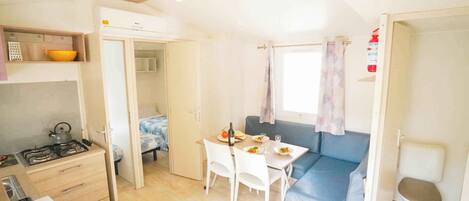 Un espacio habitable compacto con kitchenette, zona de comedor y área de estar.