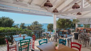 An outdoor dining area with tables and chairs, a view of the sea, and a pergola structure. - Mobile home with air conditioning, terrace and pool (Tar/Poreč)