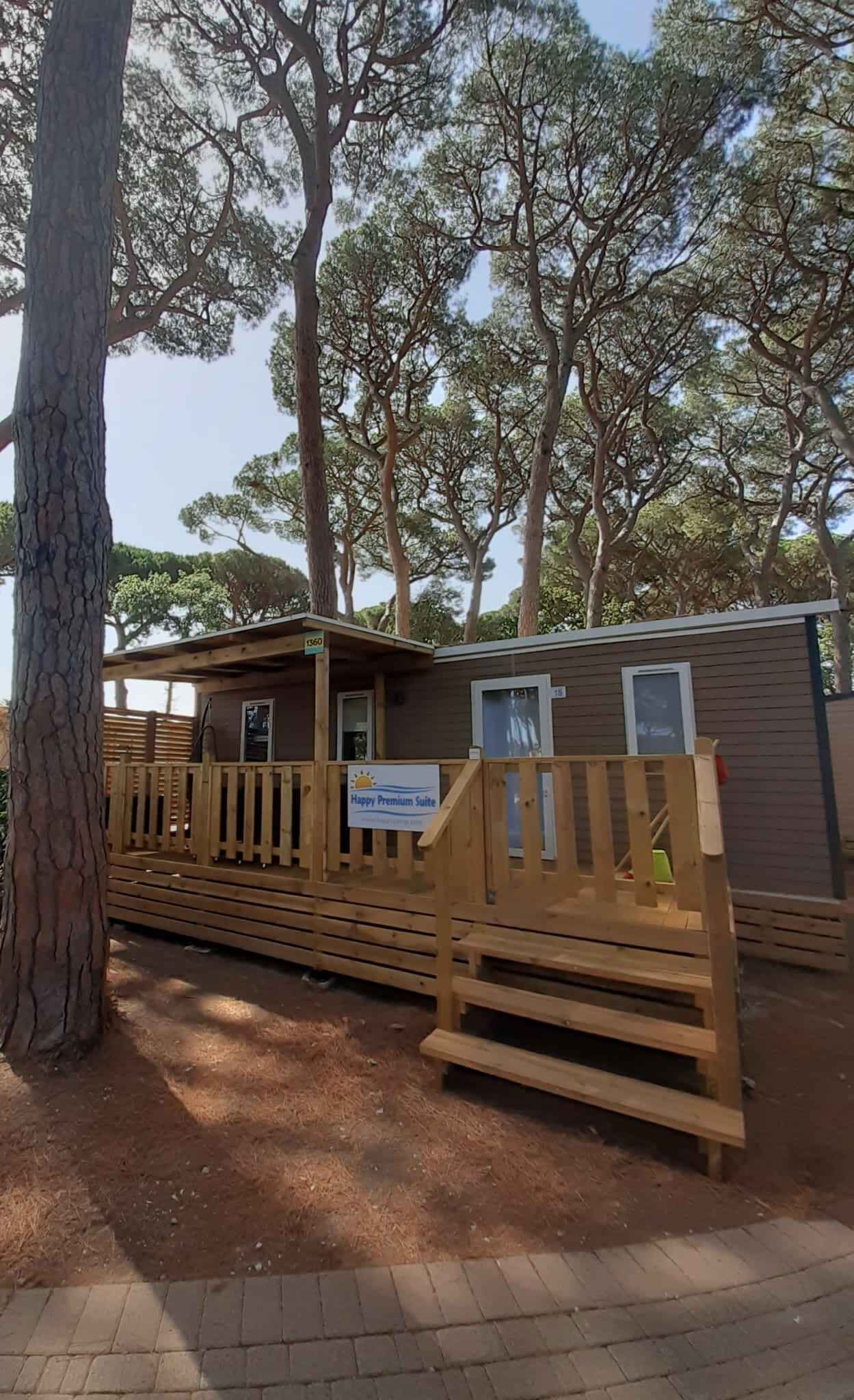 A wooden cabin with a deck, surrounded by trees.