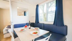 A dining area with a table, chairs, and a bench. There are plates with food on the table. - Mobilehome with air conditioning, terrace and pool (Sami)