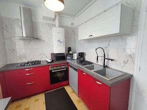 Una cocina compacta equipada con estufa a gas, microondas, cafetera y un grifo moderno.