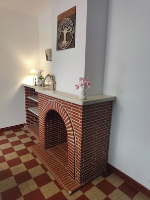 Una chimenea con diseño de ladrillo, un cuadro enmarcado encima y un florero con flores sobre la repisa.