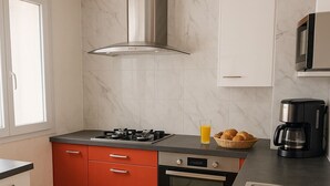 A kitchen with a gas stove, oven, and a coffee maker. - Maison le Ber-So Close to Beauval Zoo (Selles-sur-Cher)
