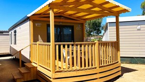 Une maison mobile dotée d’une terrasse en bois et d’un porche abrité.