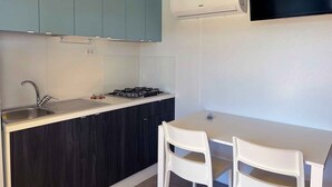 Une petite cuisine équipée d’un évier, d’une cuisinière et de deux chaises blanches autour d’une table.
