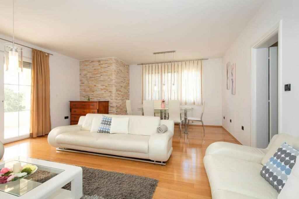 Un salon avec un canapé blanc, une table basse en verre et un mur décoratif en pierre.
