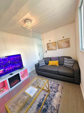 Una sala de estar con un sofá, un televisor, una araña y obras de arte en la pared.