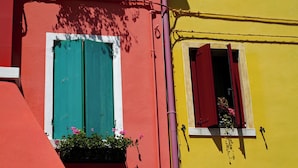 A building with two windows, one with green shutters and one with red shutters, both with flower boxes. - Holiday flat with pool (Porto Santa Margherita)