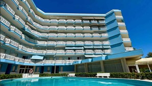 A hotel with multiple balconies, a swimming pool, and a clear blue sky. - Holiday flat with pool (Porto Santa Margherita)
