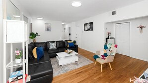 A modern living room with a black leather sofa, a white coffee table, and a colorful armchair.