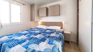 Een slaapkamer met een bed, nachtkastje, kledingkast en raam.