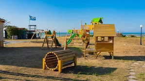 Een strand speeltuin met een glijbaan, klimconstructies en een uitkijktoren.