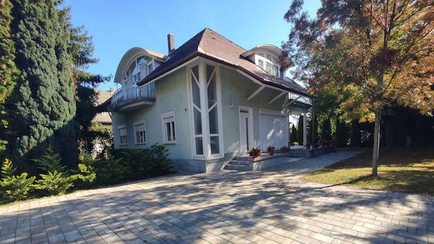 A two-story house with a symmetrical facade, a covered porch, and a paved driveway. - Holiday apartment with large balcony, American kitchen and air conditioning (Siófok)
