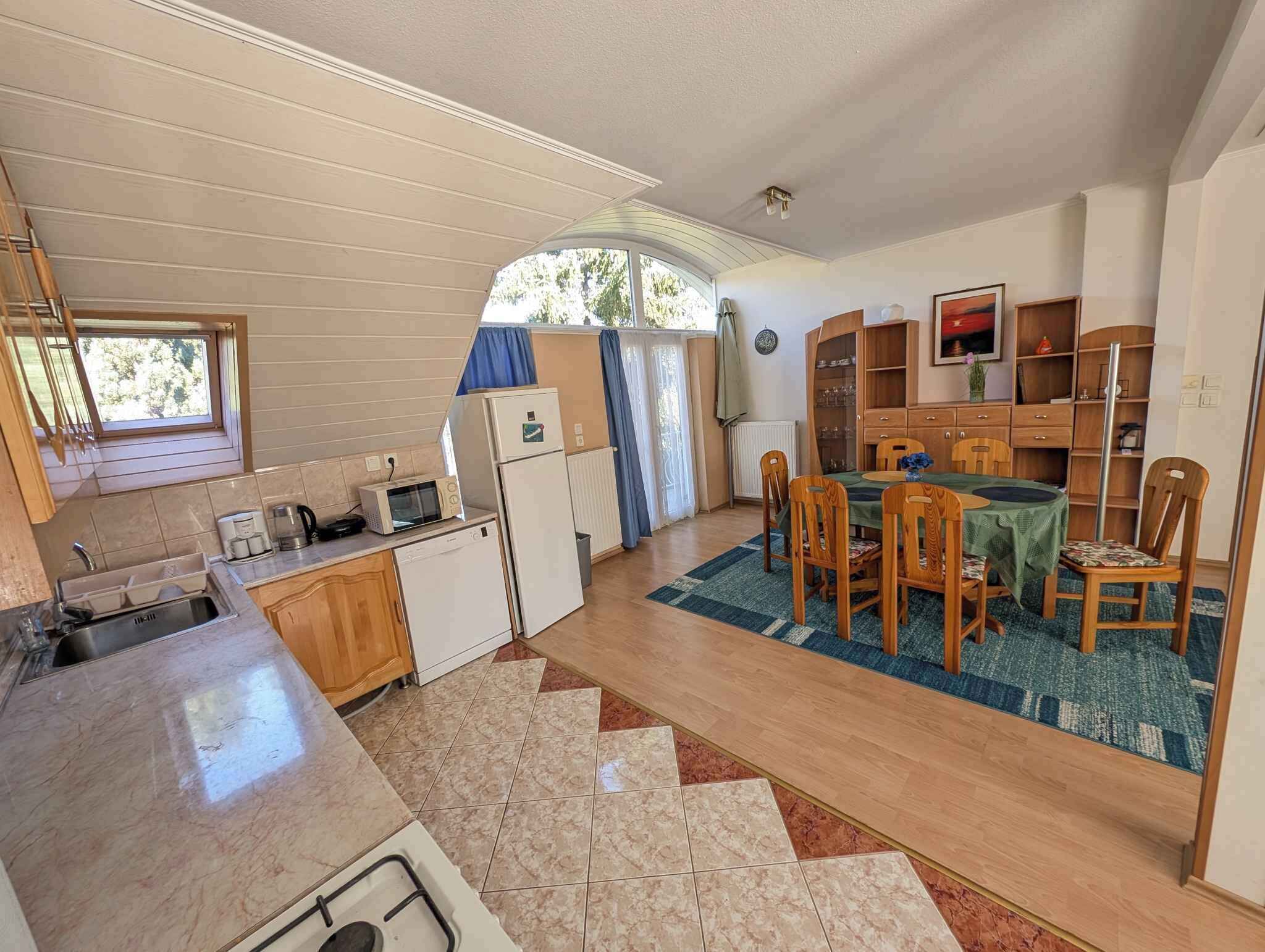 A compact kitchen with a sink, microwave, and refrigerator. There is a dining area with a table and chairs, and a small seating area with a sofa.