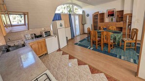 A compact kitchen with a sink, microwave, and refrigerator. There is a dining area with a table and chairs, and a small seating area with a sofa. - Holiday apartment with large balcony, American kitchen and air conditioning (Siófok)