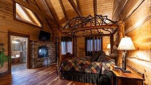 A log cabin bedroom with a stone fireplace, a four-poster bed, and a wooden ceiling. - The Sanctuary-Pet Friendly Luxury Cabin Rental, Sits on Top of the Mountain, High Speed Internet, Hot Tub, 30 Minutes to Great Smoky Mountains, in Nantahala NC (Topton)