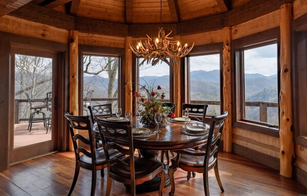 Un comedor de madera con una gran mesa dispuesta para seis personas, rodeada de sillas.
