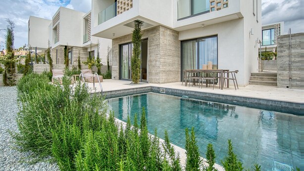 A modern residential building with a swimming pool, outdoor seating, and a well-maintained garden.