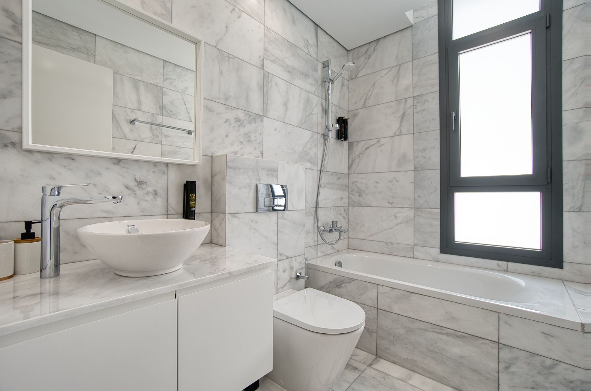 Une salle de bain moderne avec un lavabo blanc, des toilettes et une baignoire.