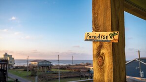 A wooden sign with the word "Paradise" and a palm tree, indicating a beachfront location.