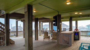 A wooden deck with a bar area, chairs, and a view of the ocean.