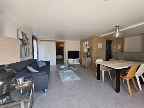 Een moderne woonkamer met een bank, salontafel en een eethoek met stoelen.