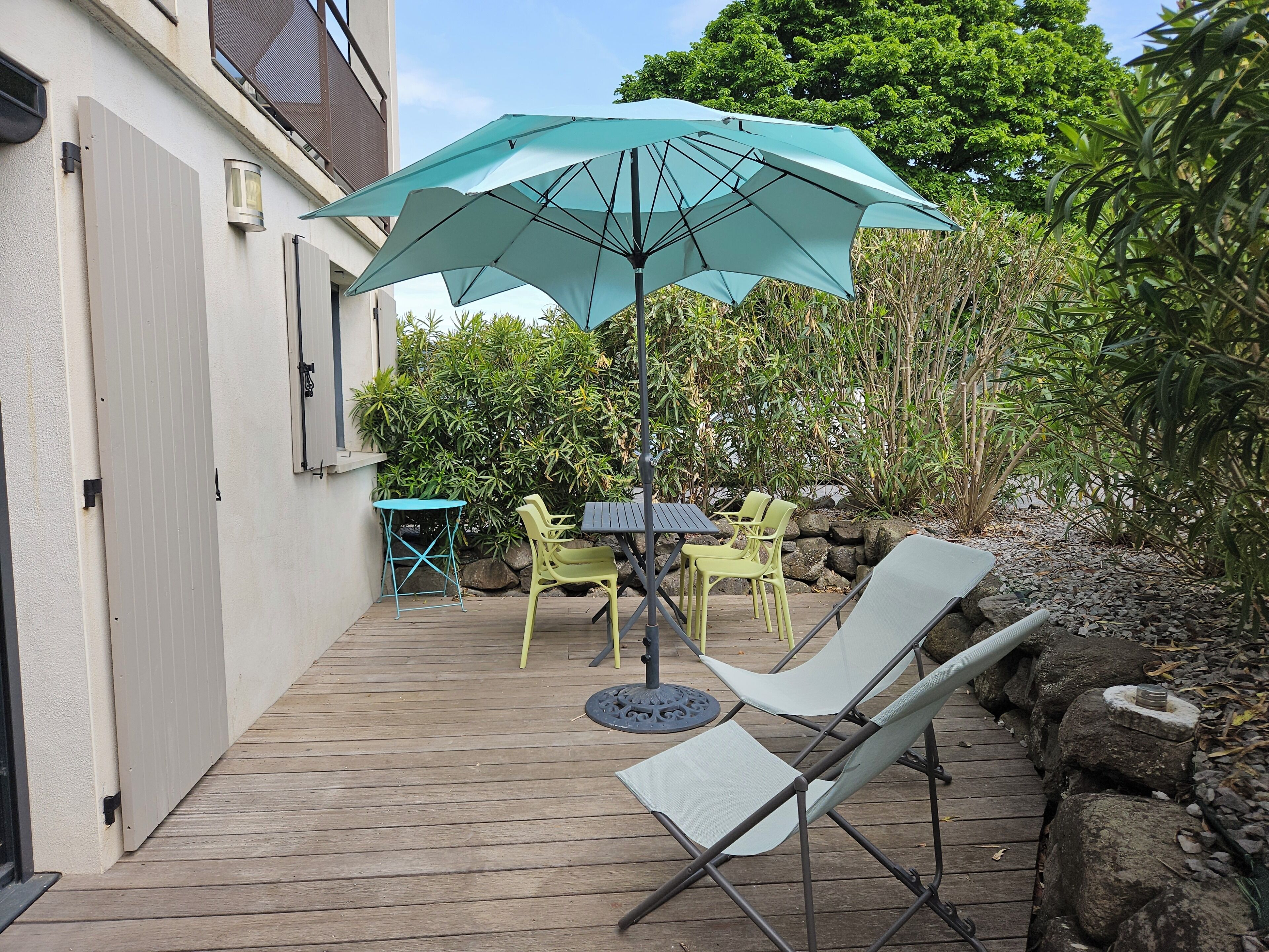 A patio with a table and chairs, a folding chair, and a large umbrella.