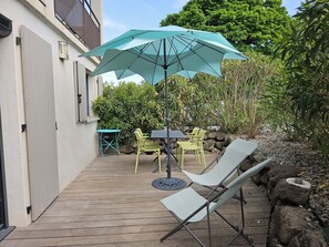 Een terras met een tafel, stoelen en een grote parasol.
