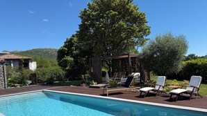 A swimming pool with lounge chairs and a pergola, surrounded by greenery and a hillside. - Les Lauriers Roses: Heated pool, unspoilt nature (Saint-Vincent-de-Barrès)