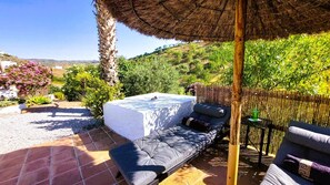 A patio with a sofa, a table, and a thatched roof.