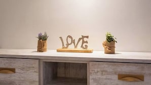 Una lámpara de pared sobre un estante de madera con dos plantas en macetas y un cartel de madera que dice "LOVE".