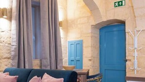 A cozy room with a dark blue sofa, stone walls, a blue door, and a green exit sign.