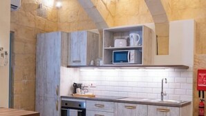 A compact kitchen with stone walls, a microwave, and a sink.