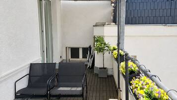 Ein Balkon mit Tisch und Stühlen, einem Blumentopf und Blumenkästen.