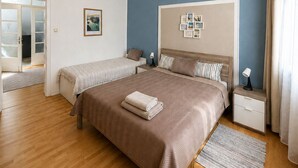 Un dormitorio con una cama grande, mesitas de noche, una lámpara colgante y vistas al exterior.