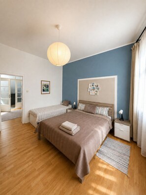 A bedroom with a large bed, bedside tables, a hanging light fixture, and a view of the outside.