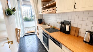 Una cocina moderna con armarios blancos, encimera de madera y suelo de baldosas negras.