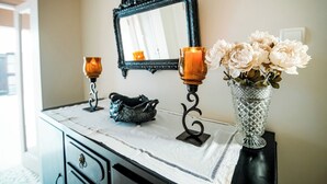 A bathroom vanity with a mirror, two candles, a vase with flowers, and a decorative item on the counter.