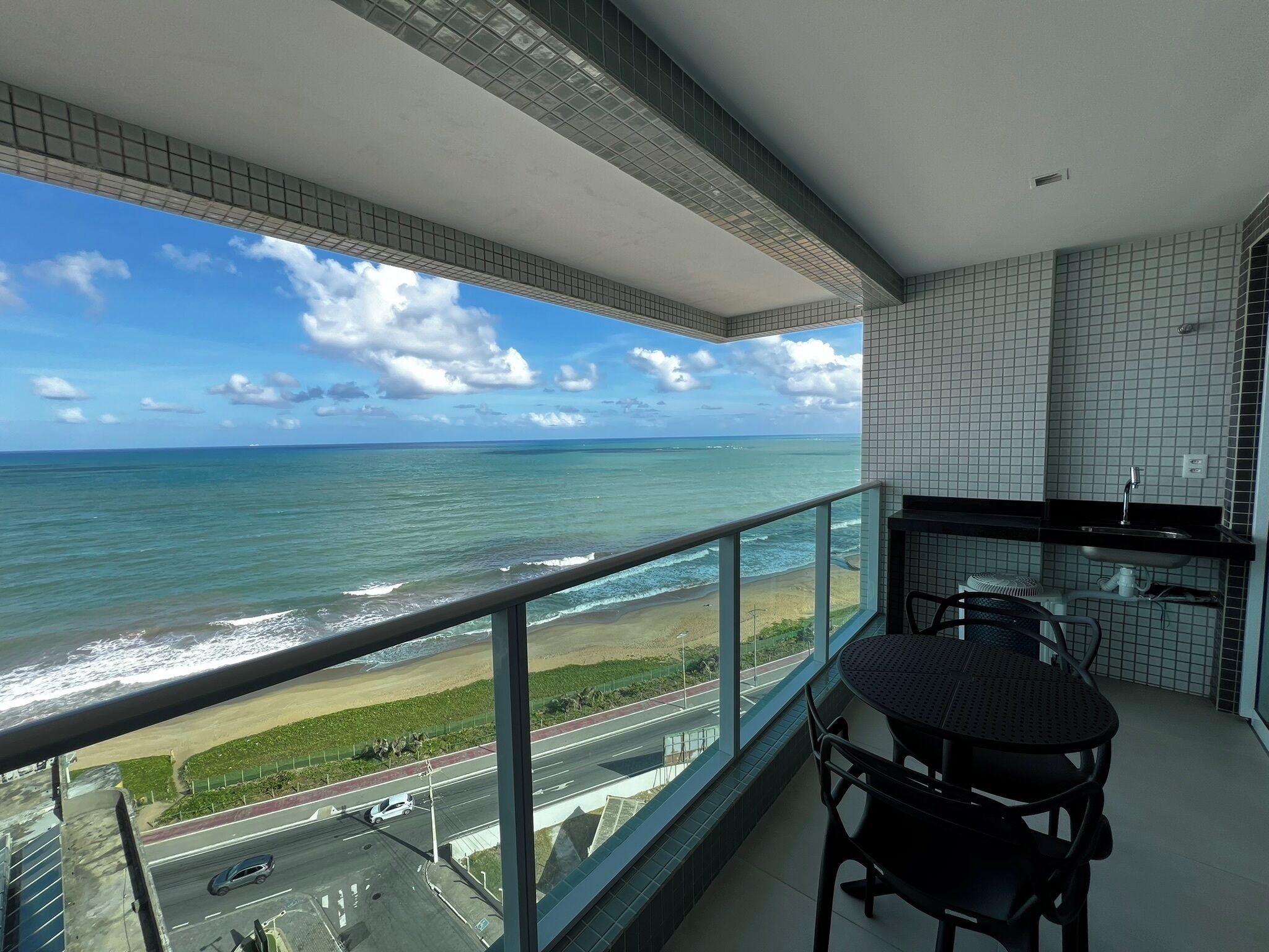 Ein Balkon mit Blick auf das Meer und eine Straße.