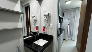 A modern bathroom with a black countertop sink, a mirror, a hairdryer, and a hand dryer. - RN STUDIO - APTO 1014 (Maceio)