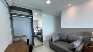 A modern, compact room with a grey sofa, a wooden table, and a mirror. - RN STUDIO - APTO 1014 (Maceio)