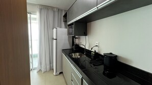 A modern kitchen with a refrigerator, microwave, stove, and sink. - RN STUDIO - APTO 1014 (Maceio)